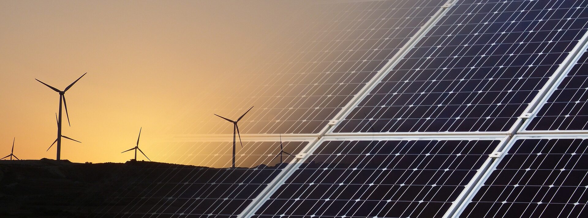 Windkrafträder links neben Solarpanelen rechts